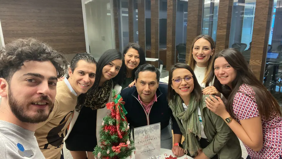 Equipo de Adver reunido alrededor de un árbol navideño