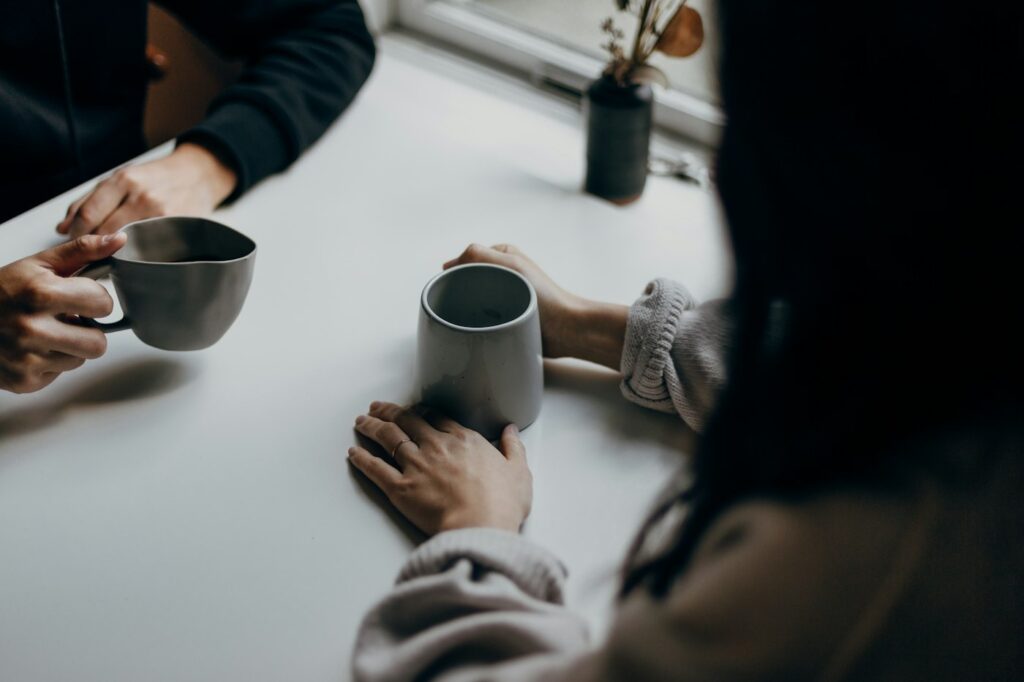 Dos personas conversan cara a cara compartiendo café