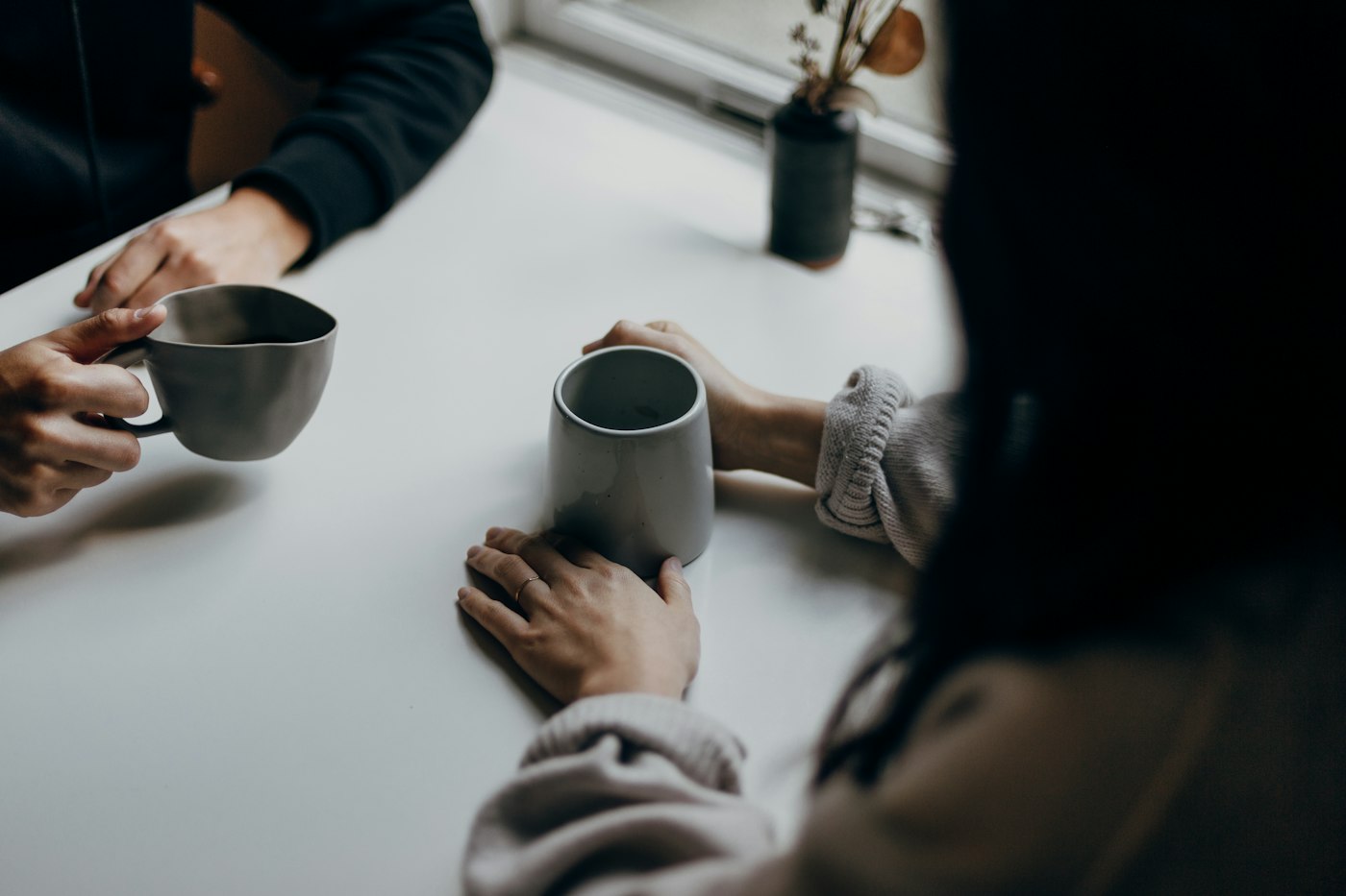 Dos personas conversan cara a cara compartiendo café