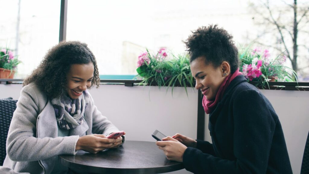 Dos amigas utilizan un teléfono inteligente en una cafetería